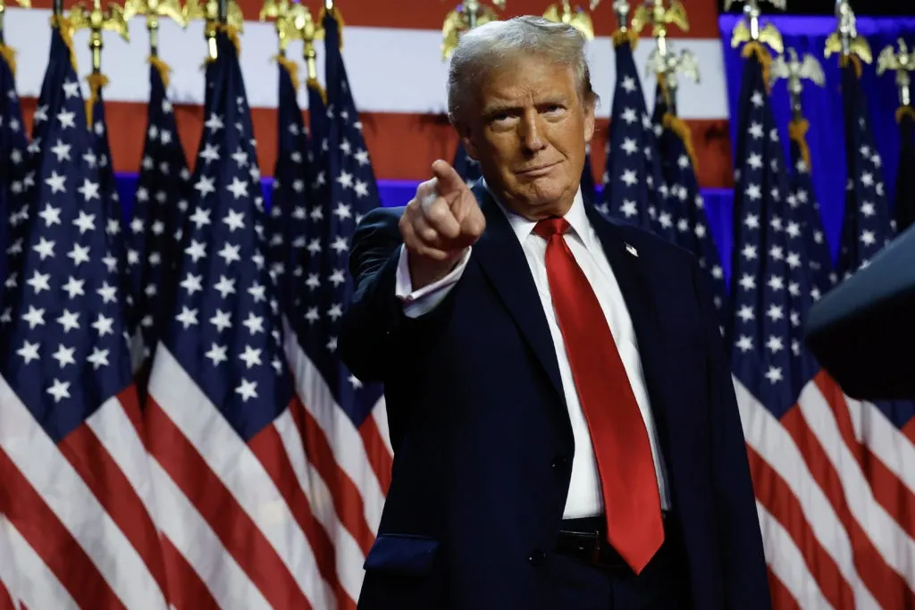 Donald Trump points at the camera with American flags